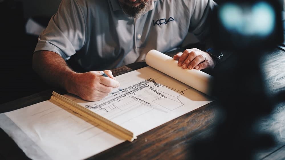 A man sketching home/building blueprint.